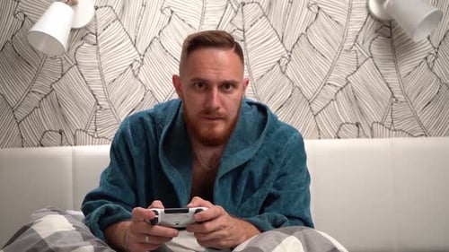 Excited Man Gaming in Bed With Controller
