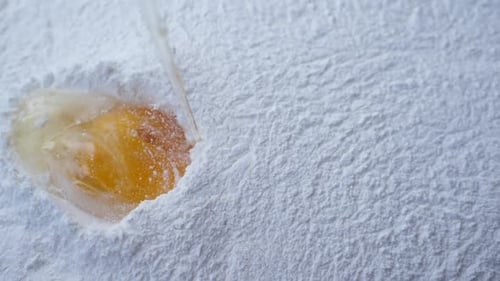 Slow motion of egg falls on a pile of flour