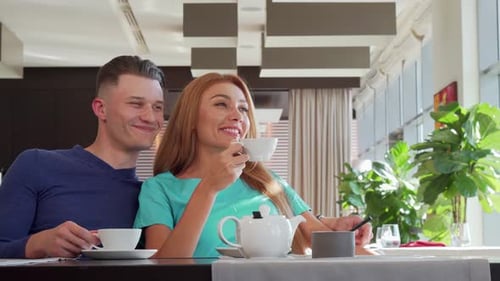 Adorável casal desfrutando de chá da manhã no café juntos, olhando para longe sonhadora