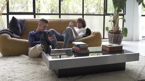 Two Young Men Relaxing on Sofa with Phones