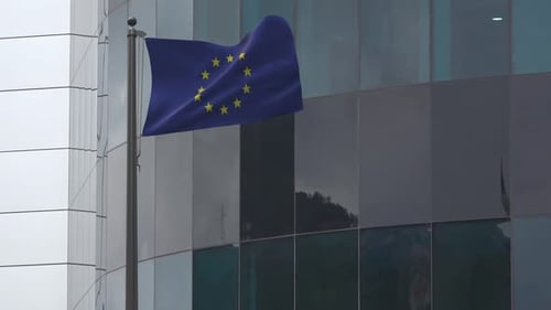 European Union Flag Waving in Front of Modern Corporate Building