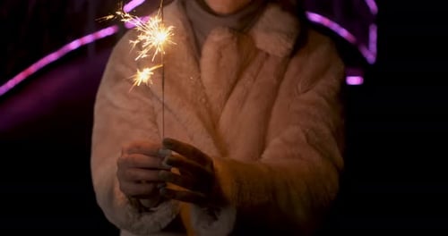 Sparklers in Young Woman Hands. Sparks Scatters in Different Directions at Neon Lights Background