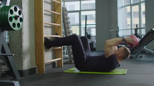 Fit Man Doing Sit-ups with Fitness Ball at Gym