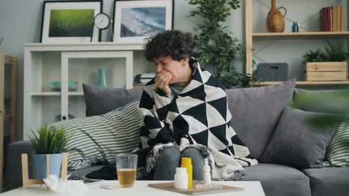 Young Lady Suffering From Cough and Sore Throat Wrapping Body in Blanket at Home