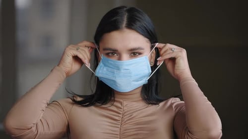 Woman Puts on a Protective Medical Face Mask