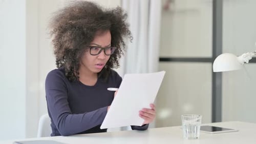 Woman Works on Papers at Desk with Concern