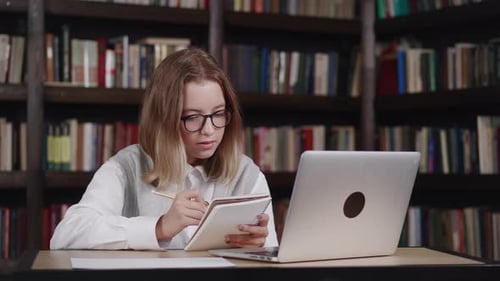 Kaukasisches junges Mädchen mit Brille macht Hausaufgaben Schulmädchen, das online mit Laptop-Herstellung studiert