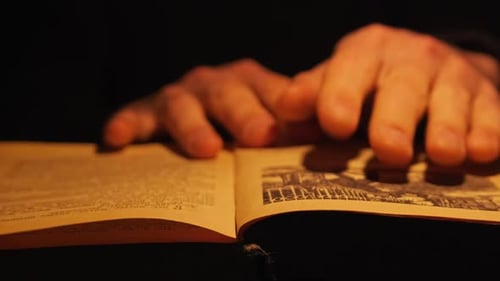 Hands Flipping Through Pages of Aged Book