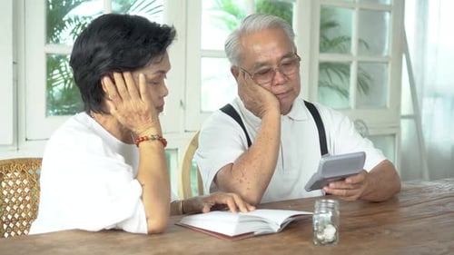 Asian Senior Couple Stressed and Serious Counting with Calculator and Having Money Problem