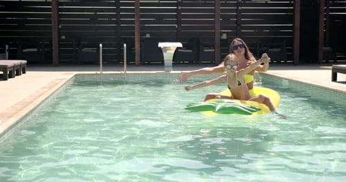 Mutter und Tochter mit aufblasbarer Ananasmatratze im Schwimmbad