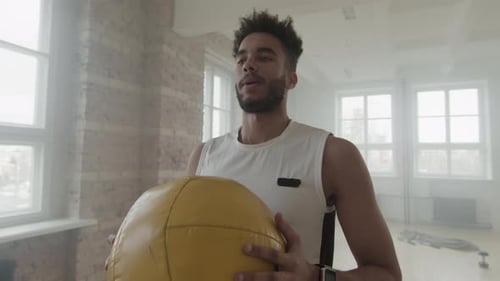 Sportler macht Kniebeugen mit Gewichtsball