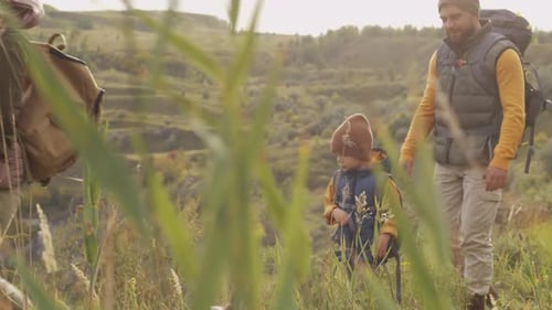 Family Hiking Together Through Grassy Rural Hills