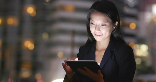 Young Businesswoman using tablet computer in city at night