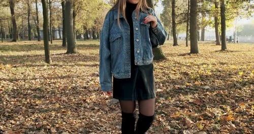 Young Woman Walk in the Autumnal Park. Girl Walks Through the Autumn City Park on a Sunny Warm Day