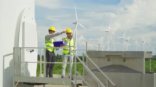 Teamwork of Asian windmill engineer group, worker working on site at wind turbines field or farm,