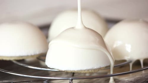 Delicious Dome Cakes Being Frosted with Cream