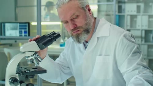 Man Using Microscope in Science Laboratory Setting