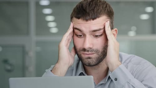 Man Working At Computer With Hands On Head
