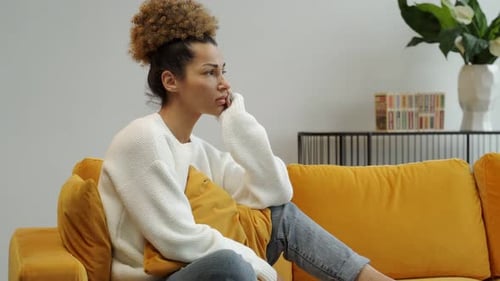 Woman Thoughtfully Posing on a Couch at Home