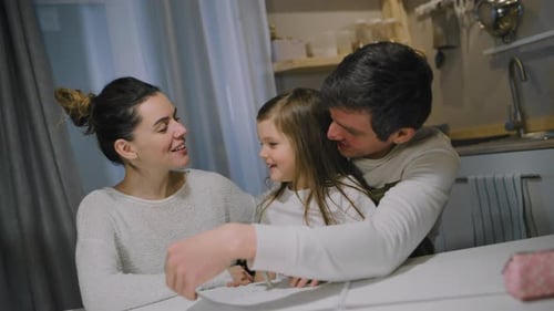 Happy Family Talking at Table in Kitchen