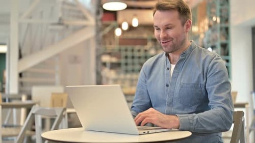 Video Chat on Laptop By Casual Man in Cafe