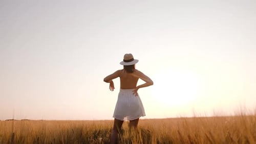 Happy Free Young Woman Dancing and Spinning Around in Slow Motion Across Field Touching Ears of
