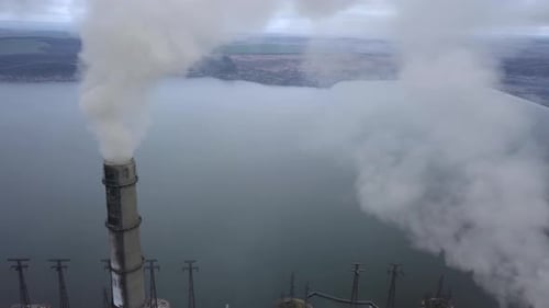 Aerial view of high chimney pipes with grey smoke from coal power plant. Production of electricity