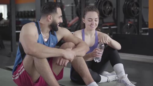 Young Middle Eastern Man Flirting with Slim Caucasian Woman in Gym