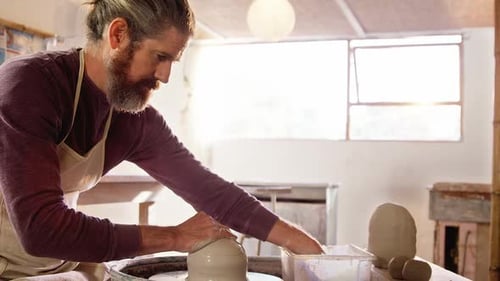Man Shaping Clay on a Pottery Wheel in Studio