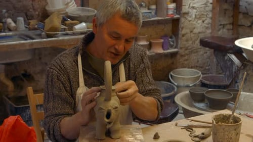 Man Carefully Shaping Clay Elephant Sculpture in Studio