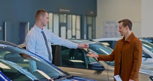 Car Dealership Salesman Hands Keys to Young Man