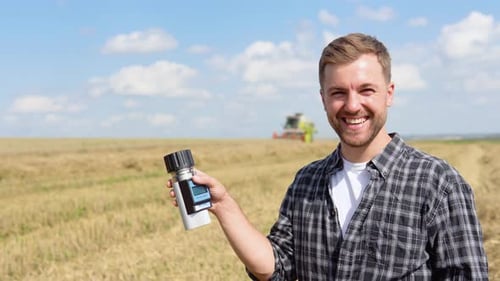 Young Farmer Inspects the State of Wheat with Special Equipment