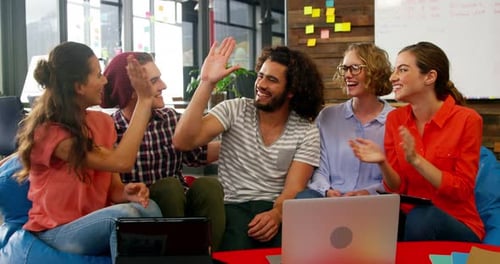 Business executives giving high fives while working in office
