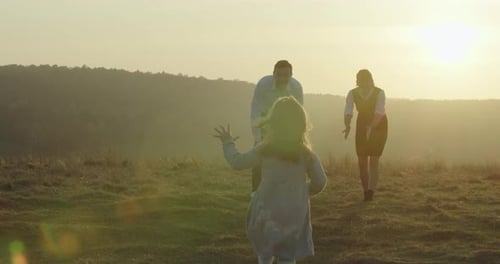 Happy Young Family Is Walking in the Field. A Little Girl Is Running To Her Parents.