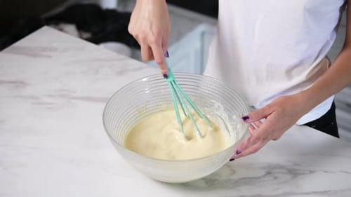 Person Mixing Batter with Whisk in Bowl