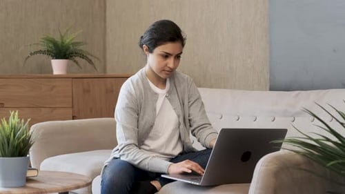 Woman Typing on Laptop While Sitting on Couch