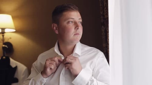 Man Buttons Shirt Before Special Event Indoors