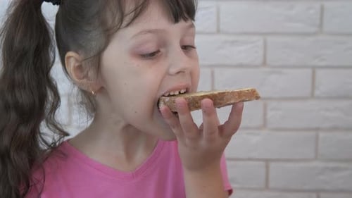 Child Eats Buttered Bread Slice at Home