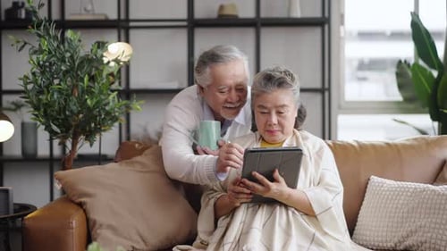 Senior Couple Enjoying Tablet Together on Couch