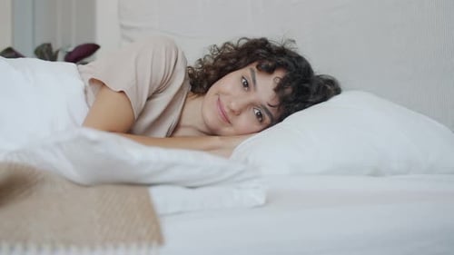 Slow Motion Portrait of Attractive Young Woman Lying in Bed Smiling Looking at Camera