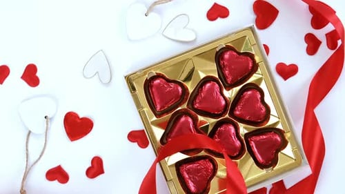 Heart-Shaped Chocolates and Red Ribbon on White Surface