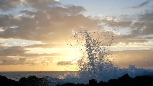 Waves Rise in the Air at Beautiful Sunset Light. Big Wave Is Crashing on Rocks and Spraying