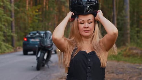 Woman Puts on Motorcycle Helmet on Rural Road