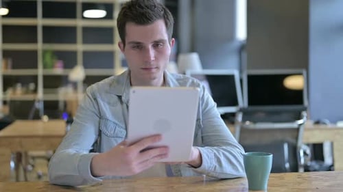 Focused Young Male Designer Using Tablet in Modern Office