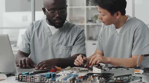Colegas multiétnicos que trabajan con electrónica en laboratorio