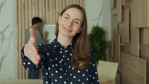 Businesswoman Extending Hand at Camera Offering Handshake Greeting Guests Looking at Camera