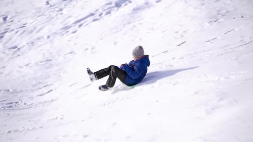 Junge, der Spaß hat und von einem Hügel reitet. Frost-Wintersaison.