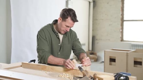 Man Using Block Plane on Wood in Workshop