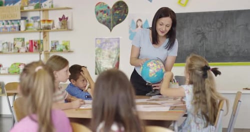 Female Teacher with Kids in Geography Class Looking at Globe