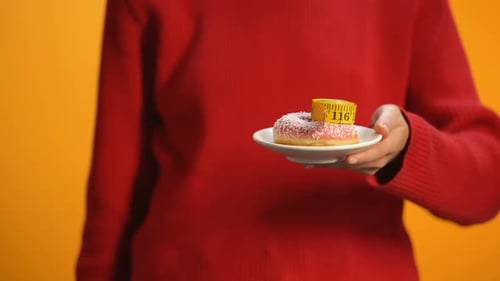 Female Holding Plate With Donut and Measuring Tape Showing Thumbs Down, Obesity